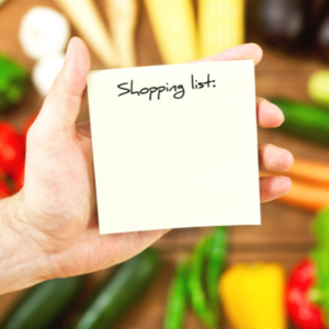 male hand holding a small notepad that says shopping list