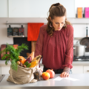 Woman in kitchen reading shopping list