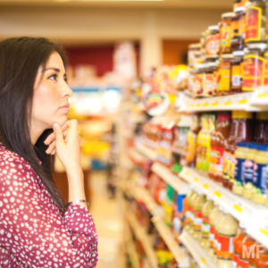 Woman looking at condiments and spices in supermarket and trying to decide.